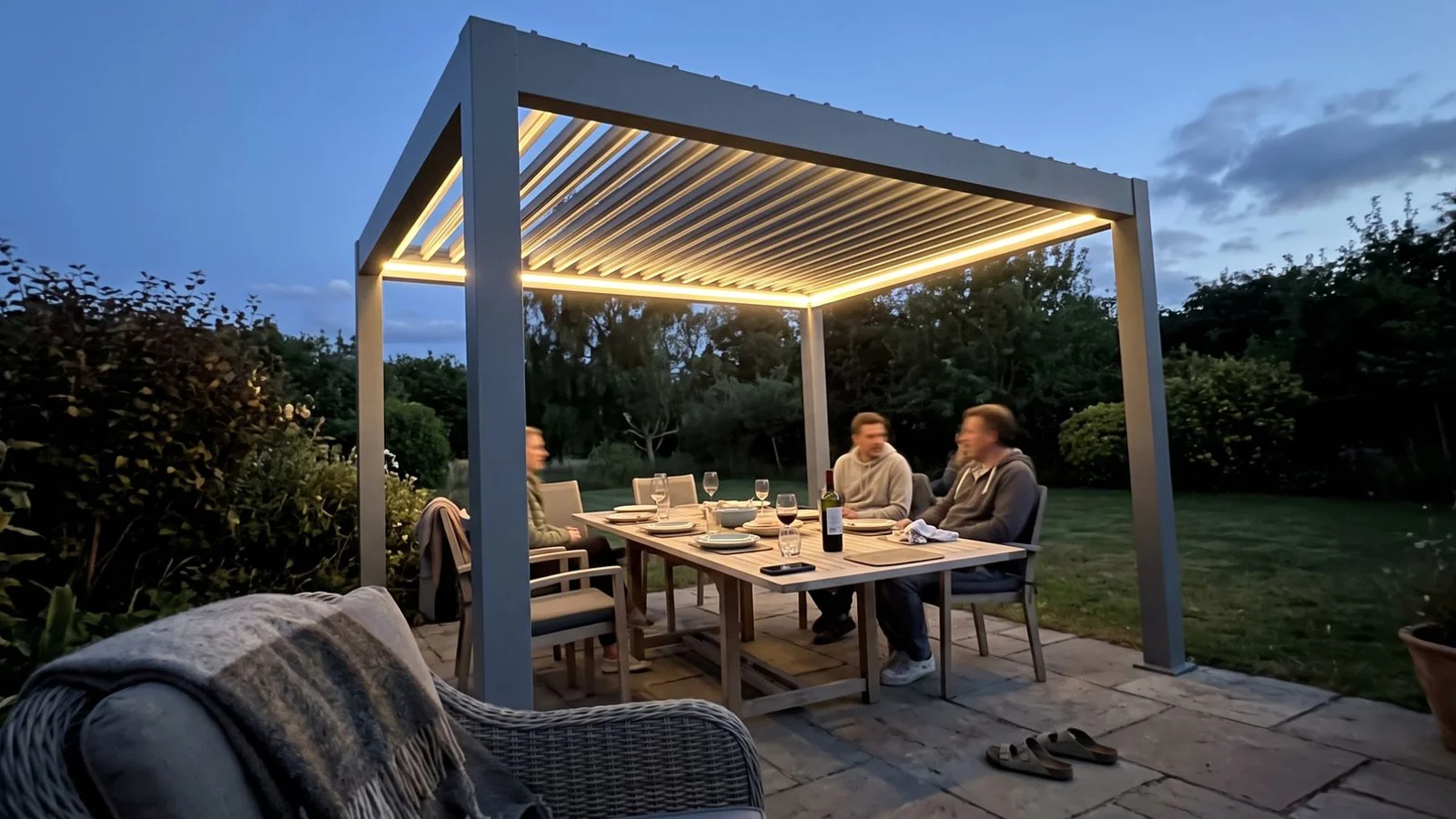Contemporary aluminium pergola with louvered roof over patio dining in a Bedfordshire garden